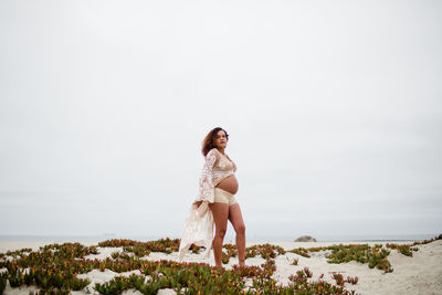 Full length of woman sitting on beach against sky