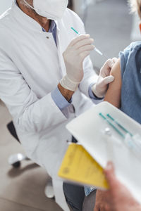 Doctor with face mask injecting antibody to boy in arms at center