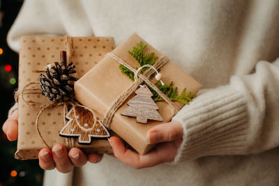 Two small gift boxes in female hands. close up. nice presents wrapped in craft paper, zero waste