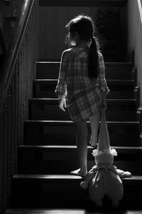 Rear view of girl holding stuffed toy on staircase