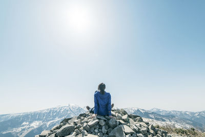 Rear view of person on snowcapped mountain against clear sky