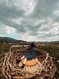Rear view of woman sitting on wicker basket