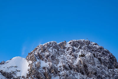 Low angle view of snowcapped mountain against clear blue sky