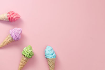Various of colourful meringue ice cream cone on pink background
