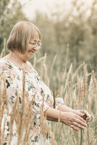 An elderly woman in the tall grass with spikelets. autumn.