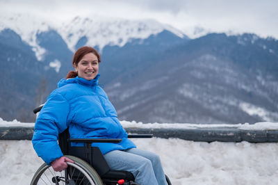 Portrait of young man sitting on snowcapped mountain