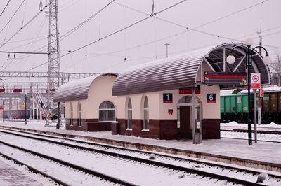 Railroad tracks by buildings against sky during winter