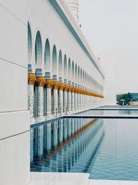 Mosque by pond against clear sky