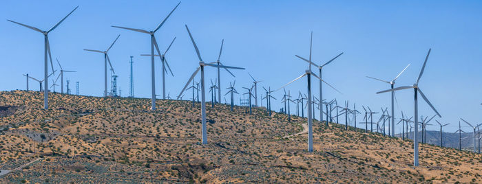 Low angle view of electricity pylon against clear blue sky