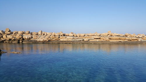 Scenic view of rocks in sea against clear blue sky