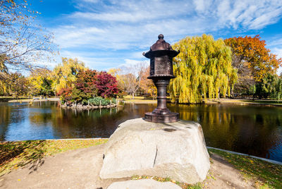 Trees by lake in park against sky during autumn