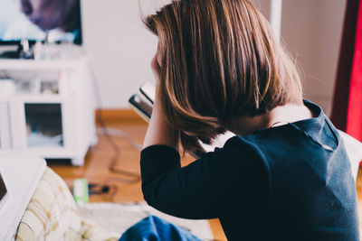 Rear view of girl sitting at home