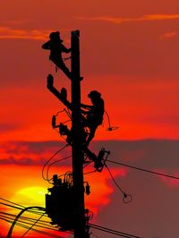Low angle view of silhouette street light against orange sky