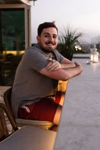 Portrait of a young man sitting on a chair in the outdoor restaurant