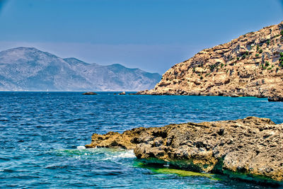 Scenic view of sea and mountains against blue sky