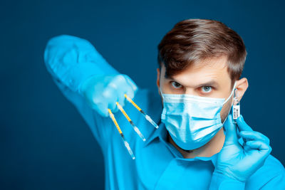 Portrait of senior man wearing mask against blue background