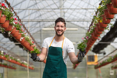 Portrait of smiling man standing in greenhouse