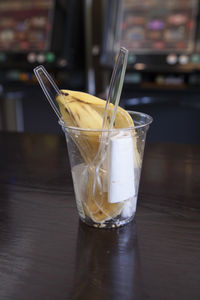 Close-up of banana peel and tissue paper with spoons in disposable cup