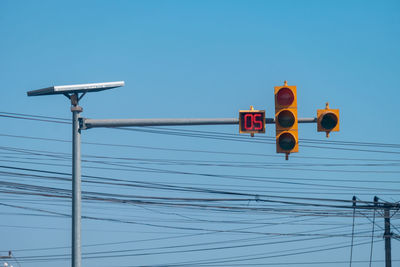 Low angle view of road signal against clear blue sky