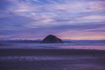 Scenic view of beach against sky at sunset