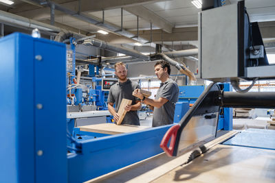Two male carpenters talking in production hall