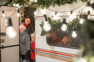 Rear view of woman standing by illuminated christmas tree