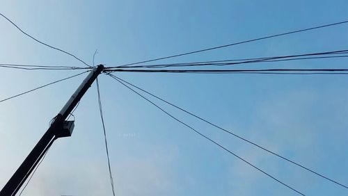 Low angle view of electricity pylon against blue sky