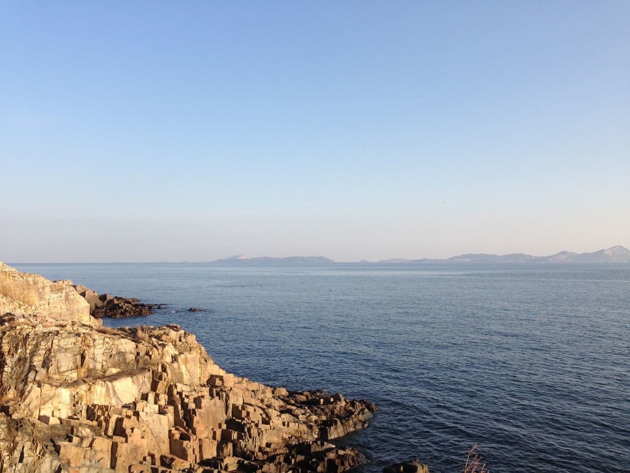 SCENIC VIEW OF SEA AND MOUNTAIN AGAINST CLEAR SKY