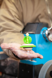 Midsection of man holding top on hand outdoors