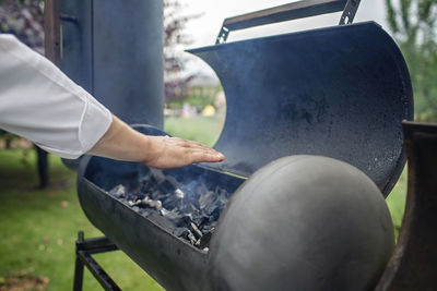 Midsection of man preparing meat on barbecue grill