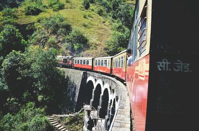 Man traveling in train on bridge against mountain