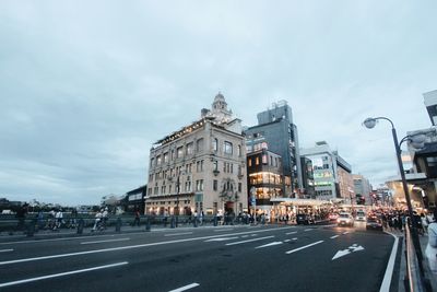 View of city street against cloudy sky