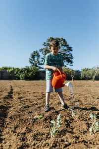 Boy watering newly planted plants in the garden