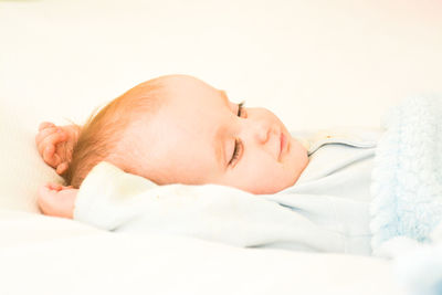 Side view of cute baby boy sleeping on bed against wall at home