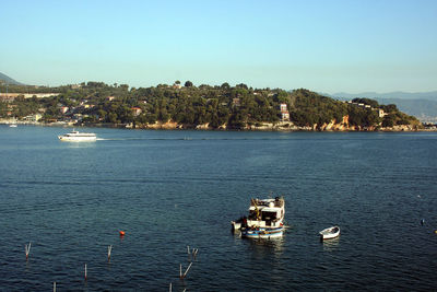 Boats sailing in sea against clear sky