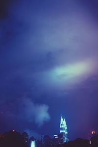 Low angle view of illuminated cityscape against cloudy sky