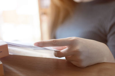 Midsection of woman holding paper with text on table