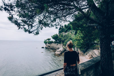 Rear view of woman looking at sea against sky