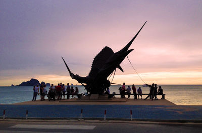 Silhouette people on beach against sky during sunset