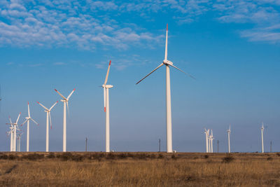 Windmills on field against sky