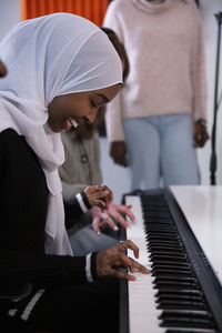 Girl in hijab playing piano in recording studio