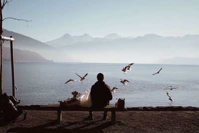 Silhouette men in sea against mountains