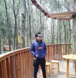 Full length of young man standing against trees in forest