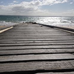 Boardwalk on pier over sea against sky