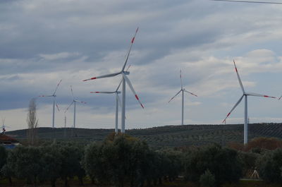 Wind turbines on field against sky