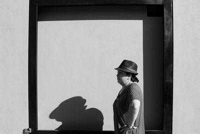 Woman looking away while standing against wall