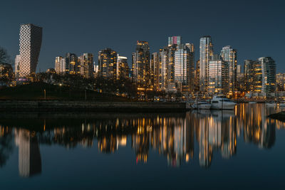 Reflection of illuminated buildings in city against sky