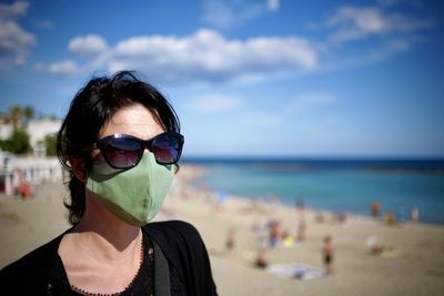 Portrait of man wearing sunglasses at beach against sky