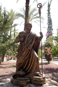 Statue by tree against sky