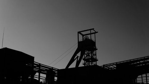 Low angle view of silhouette crane against clear sky